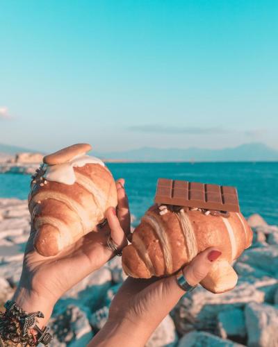 two hands holding croissants and a bar of chocolate at The Jungle Home in Naples