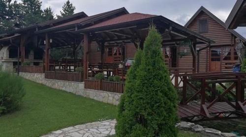 a wooden cabin with a picnic table and a tree at Zlatibor Brvnare Zakos in Zlatibor