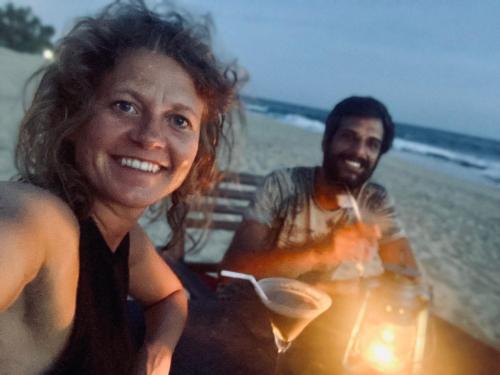a man and a woman sitting at a table on the beach at The Alpha Monkey hotel & Tree house in Tangalle