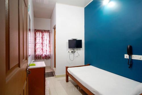 a small room with a bed and a blue wall at Reach Residency in Cochin