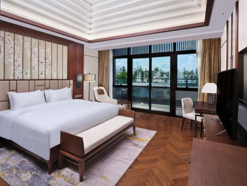 una camera da letto con un grande letto bianco e una televisione di HUALUXE Suzhou Bay Hot Spring Resort a Suzhou