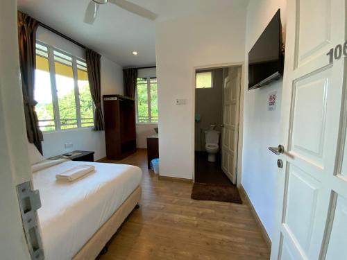 a bedroom with a bed and a toilet and a door at Highlanders Garden Guesthouse at Arundina Cameron Highlands in Cameron Highlands