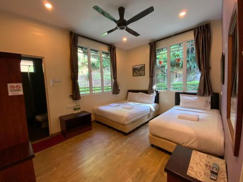a bedroom with two beds and a ceiling fan at Highlanders Garden Guesthouse at Arundina Cameron Highlands in Cameron Highlands