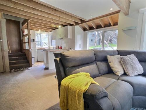 a living room with a couch and a kitchen at Faithfulls Chalet, alpine-getaways in Dinner Plain