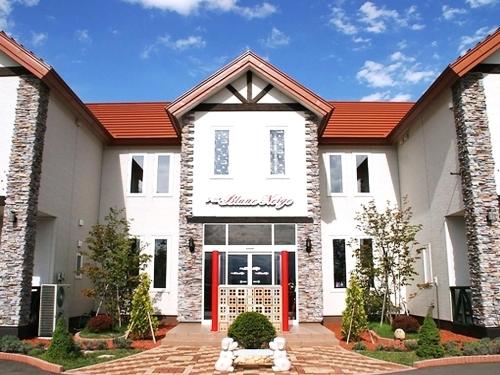 a white house with a dog in front of it at Petit Hotel Blaneneige in Nakafurano
