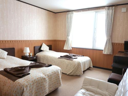 a hotel room with two beds and a window at Petit Hotel Blaneneige in Nakafurano