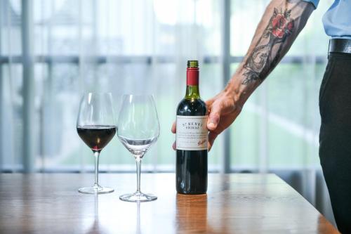 a man holding a bottle of wine next to two glasses at Powerhouse Hotel Tamworth by Rydges in Tamworth