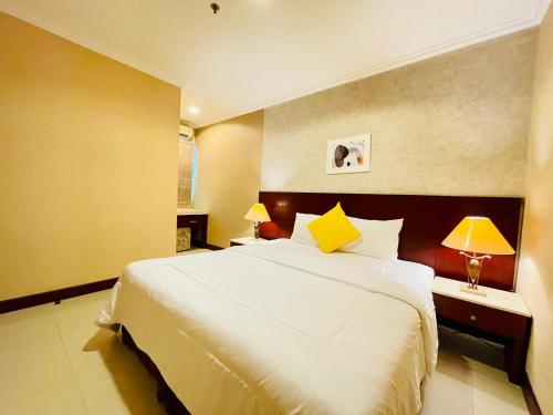 une chambre avec un grand lit blanc et deux lampes dans l'établissement Luxury 2BR Apartment @ Galeri Ciumbuleuit with Best View @ 1st Tower, à Bandung
