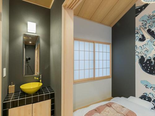 La salle de bains est pourvue d'un lavabo jaune et d'un miroir. dans l'établissement YADOYA 根岸, à Tokyo