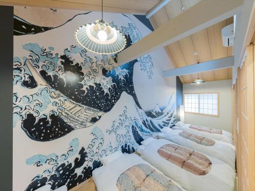 Cette chambre comprend 2 lits et une fresque murale représentant un tsunami. dans l'établissement YADOYA 根岸, à Tokyo