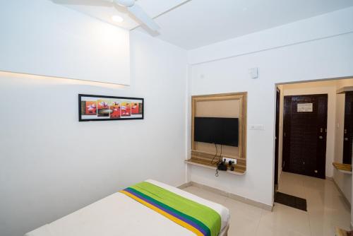 a white room with a bed and a tv at Hotel Dhruv Palace Bangalore Jakkur in Bengaluru