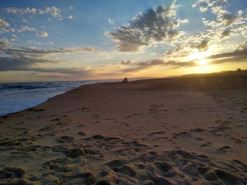 a sunset on a beach with footprints in the sand at Nio de Baixo in La Pedrera