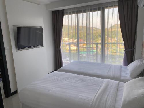 ein Hotelzimmer mit einem Bett und einem großen Fenster in der Unterkunft AYA APARTMENTS IN MBC in Mai Khao Beach