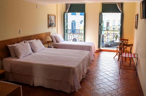 a hotel room with two beds and a balcony at Hotel Cruz do Pascoal in Salvador