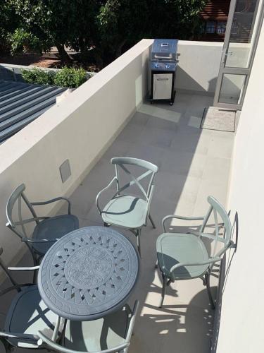 a table and four chairs on a balcony with a grill at At Last Glentana Apartment in Groot Brak Rivier