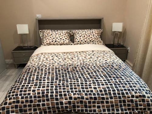 a bed with a black and white comforter and two lamps at New Contemporary Guest House in Studio City Hills in Los Angeles