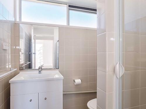 a white bathroom with a sink and a shower at Shoreline, 4,7 Victoria Parade - Views over Fly Point and close to Nelson Bay Marina in Nelson Bay