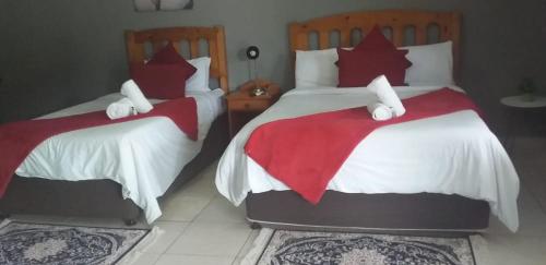 1 dormitorio con 2 camas y almohadas rojas y blancas en Mbazwana Inn en Mbazwana