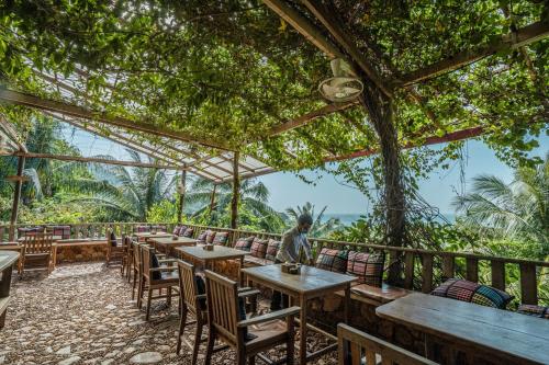 
a patio area with tables, chairs and umbrellas at Veranda Natural Resort in Kep
