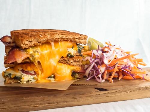 a sandwich on a cutting board with a salad at Busoan Library & Hostel in Machida