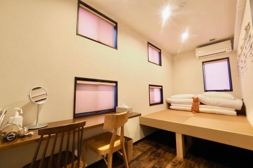 a room with a desk with a computer and windows at Nekokura Hostel in Fukuoka