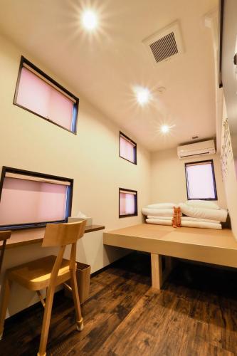 a room with a desk and a bed with windows at Nekokura Hostel in Fukuoka