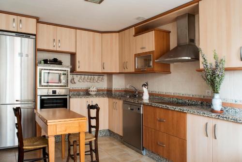 a kitchen with wooden cabinets and a table and a stove at Casa Montesol in Cáceres
