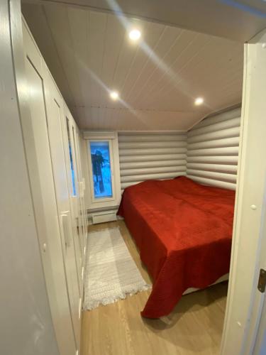 a small bedroom with a red bed and a window at Villa Muikkupolku in Kokkola