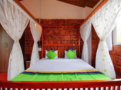 a bedroom with a bed with white curtains and green pillows at Treebo The Appa'S Resort in Mahabaleshwar