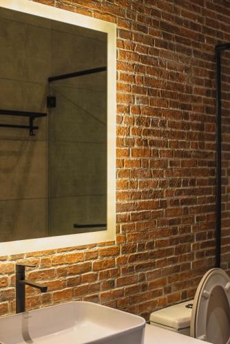 a bathroom with a white sink and a brick wall at Alivila in Muar