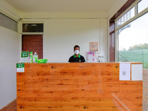 a person wearing a mask behind a wooden counter at Treebo The Appa'S Resort in Mahabaleshwar