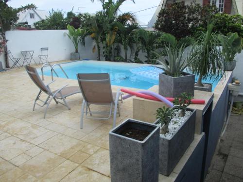 een zwembad met 2 stoelen en een tafel bij chez lulu in Saint-Joseph