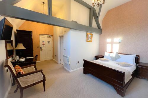 a bedroom with a bed and a chair in a room at Castle Bromwich Hall; Sure Hotel Collection by Best Western in Birmingham