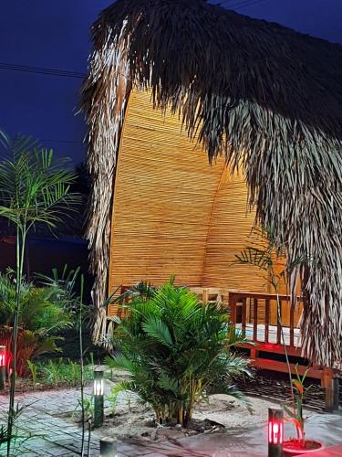 a building with a straw roof and some palm trees at Homestay Khoáng nóng Thông Nguyên in Nam Giang