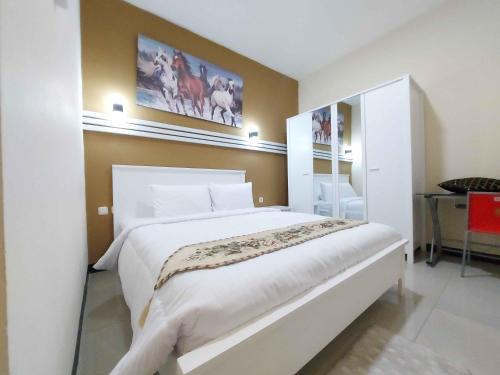 1 dormitorio con 1 cama blanca grande y escritorio en Rons City Hotel near Simpang Lima Semarang Mitra RedDoorz en Semarang