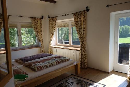 a bedroom with a bed and two windows at Ferienwohnung Hergesell in Marktschellenberg