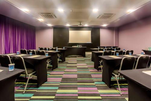 a conference room with tables and chairs and a screen at ibis Styles Confins Aeroporto in Lagoa Santa