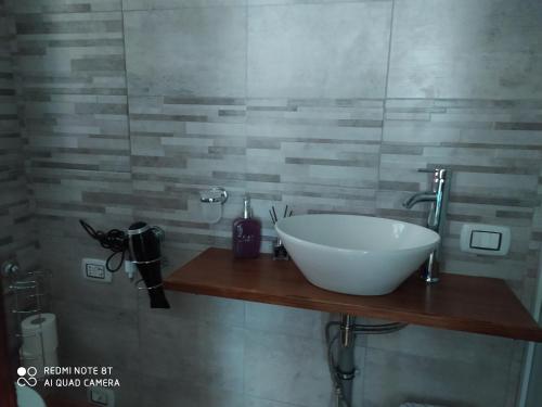 a bathroom with a white bowl sink on a wooden counter at Holiday rooms with private bathroom in Acilia