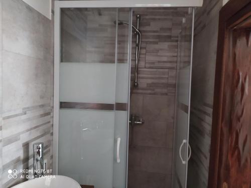 een douche met een glazen deur in de badkamer bij Holiday rooms with private bathroom in Acilia