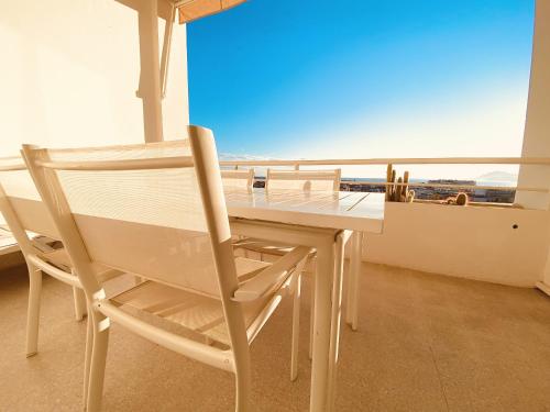 une table et des chaises de salle à manger blanches avec vue sur l'océan dans l'établissement GALIAfon5581, à Cannes