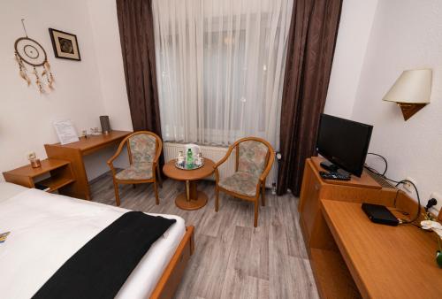 a hotel room with a bed and a desk with a television at Hotel am Schlosspark Essen in Essen