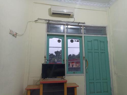 a room with a green door and a television at Hoya Residence Syariah in Sodong