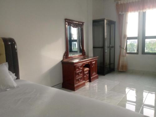 a bedroom with a wooden dresser and a mirror at Homestay Hilal Meulaboh Syariah RedPartner in Sua Dokata