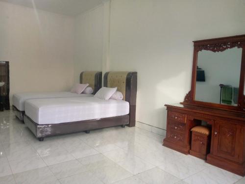 a bedroom with a bed and a dresser and a mirror at Homestay Hilal Meulaboh Syariah RedPartner in Sua Dokata