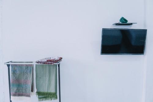 einen TV, der an einer Wand neben einem Fenster hängt in der Unterkunft Homestay Hilal Meulaboh Syariah RedPartner in Sua Dokata