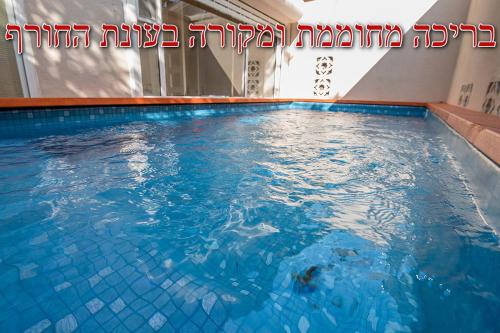a swimming pool with blue water in a building at Eden's Boutique in Had Nes