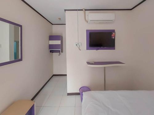 a room with a bed and a sink and a tv at RedDoorz @ Jalan Ahmad Yani in Karawang