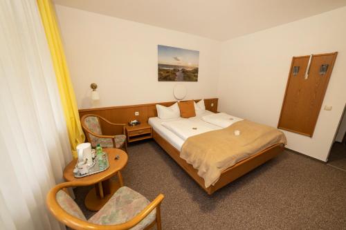 a bedroom with a bed and a table and chairs at Hotel am Schlosspark Essen in Essen