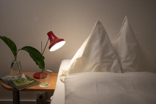 a bed with white pillows and a table with a lamp at Kloster Ilanz in Ilanz