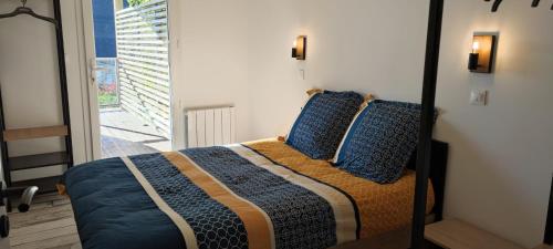 a bedroom with a bed with blue pillows at Les terrasse du rody, vue mer . in Guipavas